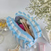 Medium sky-blue striped cosmetic bag with ruffles