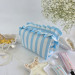 Medium sky-blue striped cosmetic bag with ruffles